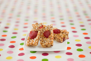 Müsliriegel mit Erdbeeren auf gepunkteter Tischdecke