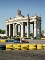 Man driving a go-kart in front of a main entrance to All-Russia Exhibition Centre, Moscow, Russia