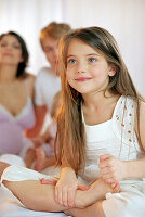 Girl sitting on bed holding feet, smiling, portrait