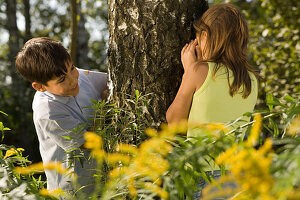 Girl and boy playing hide-and-seek, children's birthday party