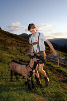 Sennerin, 2 Zicklein, Fütterung in der Dämmerung, Karseggalm, Nationalpark Hohe Tauern, Salzburger Land, Österreich