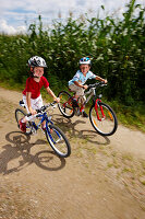 Zwei Kinder (6-7 Jahre) fahren Fahrrad, Bayern, Deutschland