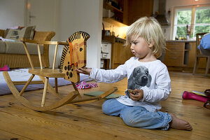 Girl (2 years) playing with rocking horse, Berg, Bavaria, Germany