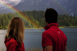 Young couple watching rainbow, lake Lautersee, Mittenwald, Werdenfelser Land, Upper Bavaria, Germany