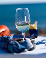 Glass of white wine on an outdoor table, lobster, napkin