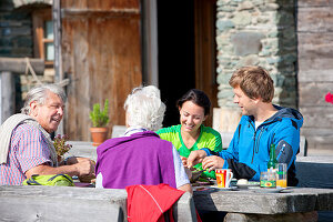 Vier Wanderer beim Essen vor einer Almhütte, Steiermark, Österreich