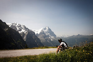 Radfahrer rastet an Passstraße, Eiger und Mönch im Hintergrund, Abfahrt von der Grossen Scheidegg nach Grindelwald, Berner Oberland, Schweiz