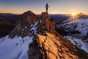 Wanderer, Kletterer klettert auf exponierten Grat in den Tiroler Alpen und blickt dem Sonnenuntergang entgegen, Wildlahnertal, Österreich