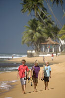 Junge Surfer beim Spaziergang am Strand von Hikkaduwa, Sri Lanka