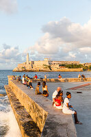 Tourists and local people and fisherman at Malecon, historic town center, old town, Habana Vieja, Habana Centro, opposite Castillo De Los Tres Reyes Del Morro, family travel to Cuba, holiday, time-out, adventure, Havana, Cuba, Caribbean island