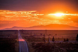 Cars driving on remote road at sunset