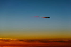 Flugzeug mit Kondensstreifen kurz vor dem Sonnenaufgang