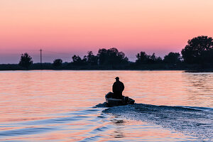 Boot im Donaudelta. Der Mann lenkt mit Gewichtsverlagerung, die Hände in den Hosentaschen, nach Hause. Mila 23, Tulcea, Rumänien.