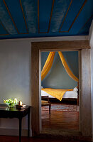 Blick in einen Raum mit einem Bett, hellgelber Stoff, Palacio Belmont, in Lissabon, Portugal.