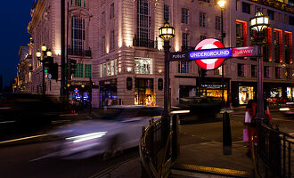 Abendaufnahme, Verkehr und Londoner U-Bahnzeichen. Piccadilly Circus in London, England, Großbritannien