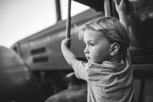 Boy climbs on a tractor, black and white