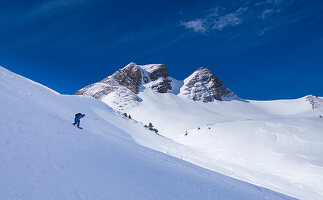 Snowboarders in deep snow in front of mountain peaks in Damuels in winter in the snow