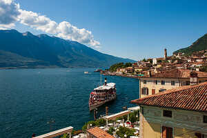 A ship full of tourists docks in Limone del Garda on the lake of the same name, on a sunny day. Brescia. Italy