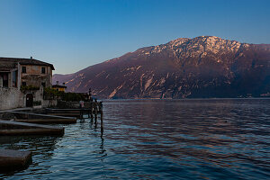 Two tourists await the sunset on the shore of Lake Garda in Limone sul Garda.