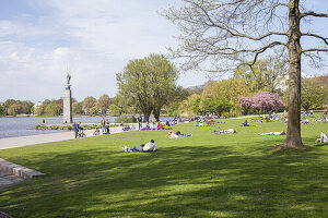 People relaxing on a meadow at the Alster in Hamburg in spring, Germany