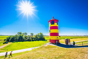  The Pilsum lighthouse on the North Sea dike in summer with blue sky near Greetsiel, municipality of Krummhörn, Lower Saxony, Germany 