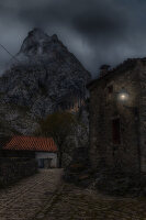  Cobblestone alley in mountain village. Mountain in background. Street lamp. Dark clouds. Bulnes Asturias, Spain. 