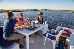 Freunde genießen das Abendessen an Deck eines Le Boat (Emerald Star) Magnifique Hausboots in der Marina von Clonmacnoise am Fluss Shannon, Clonmacnoise, County Offaly, Irland, Europa