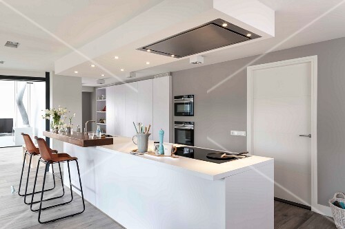 A Modern White Kitchen With An Island With An Illuminated