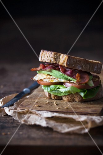 Sandwich with fried egg, bacon, avokado and tomato